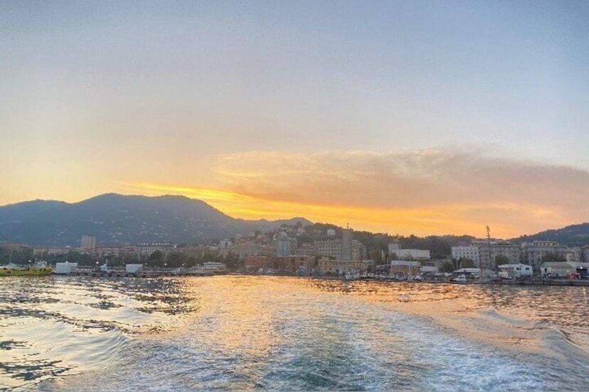Een kuststadsgezicht bij zonsondergang, met bergen op de achtergrond. 3