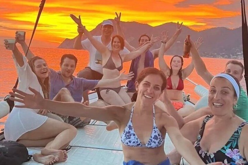 Een groep mensen op een boot, met een zonsondergang op de achtergrond. 4
