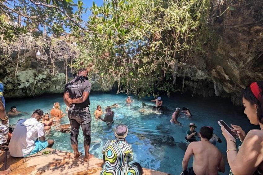 Un grupo de personas nadando en una piscina natural rodeada de árboles y acantilados rocosos. 5