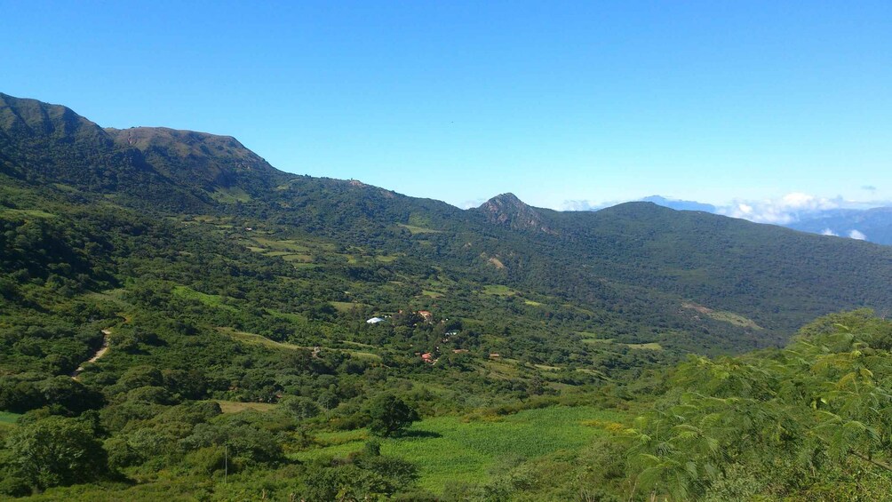 A mountainous landscape with dense greenery and scattered buildings. 1