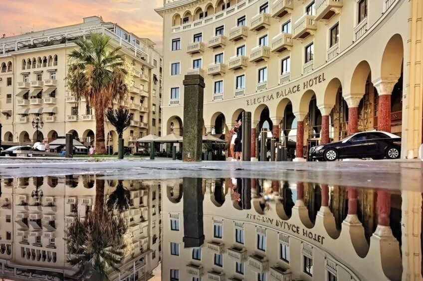 A hotel with a reflection in the water, palm trees, and a clear sky. 1