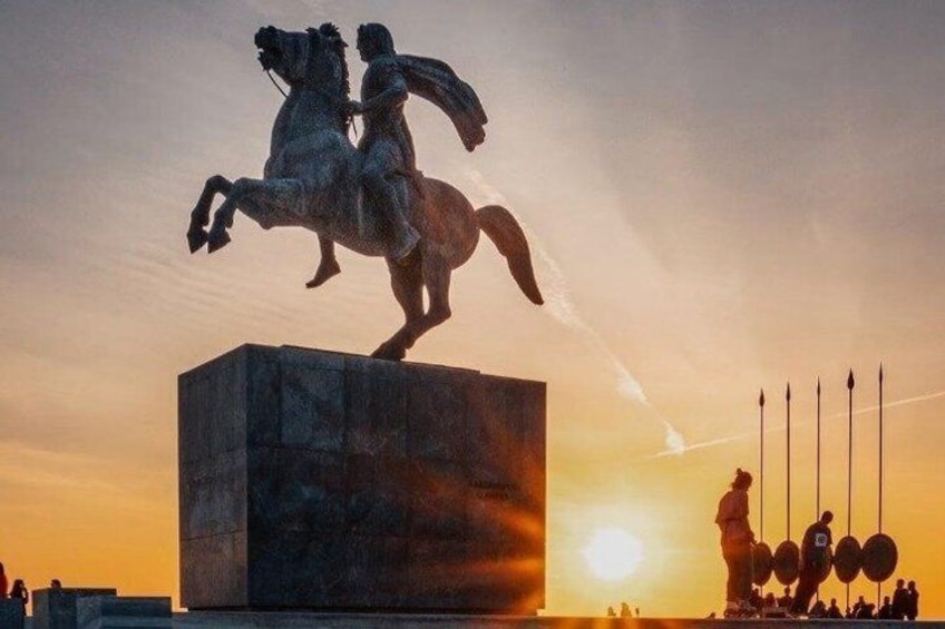 A statue of a figure on horseback, a sunset in the background, and a group of people in the foreground. 2