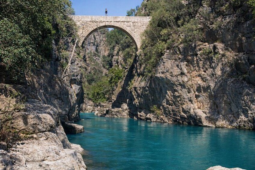 Un puente de piedra sobre un río, rodeado de riscos y vegetación. 1