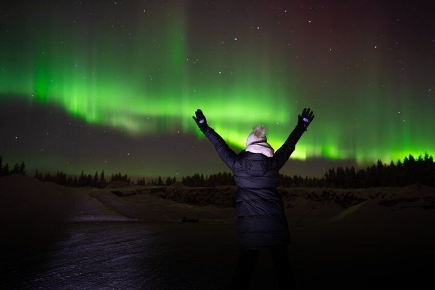 En person står med armene løftet og ser mod nordlys. 4