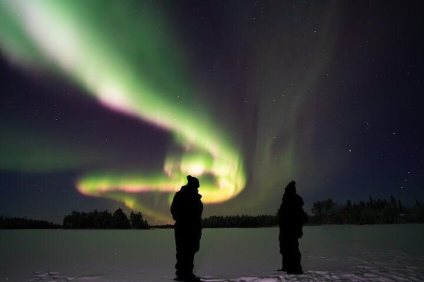 To personer står på is og ser nordlys. 5