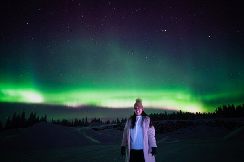 En person står i et snækkedækket landskab under en nattehimmel med nordlys. 3