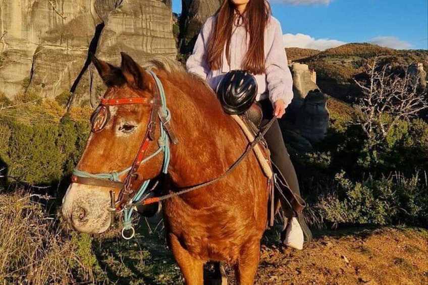 A person riding a horse with a helmet, in a natural landscape with rocky formations. 3