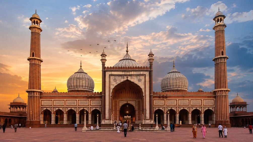 A large mosque with multiple domes and minarets, surrounded by a spacious courtyard with people walking around. 2