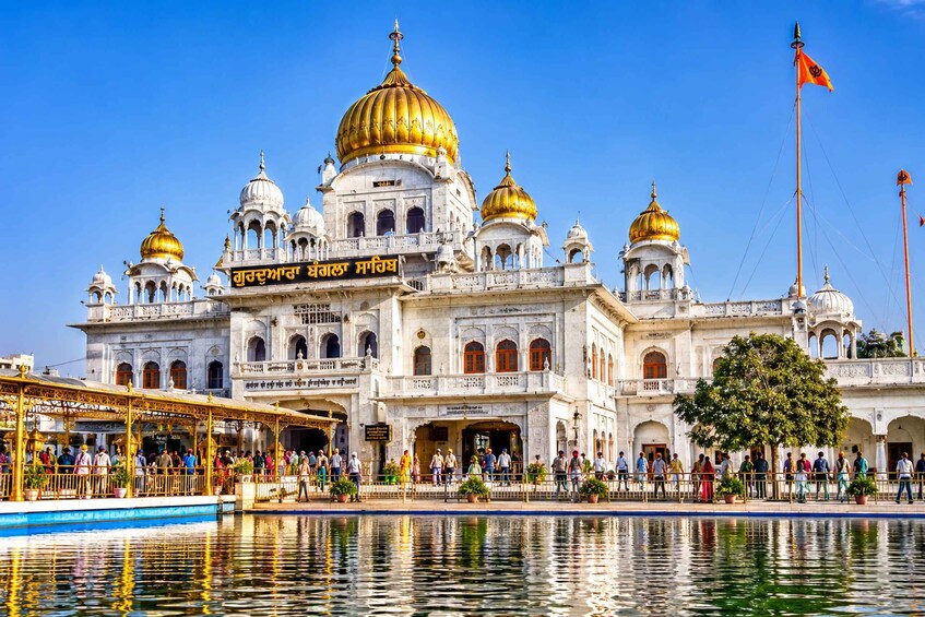 A large white building with golden domes and a flag. 3