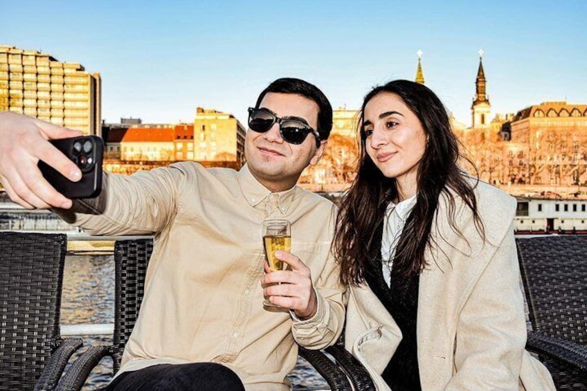 Two people taking a selfie with a cityscape in the background. 1
