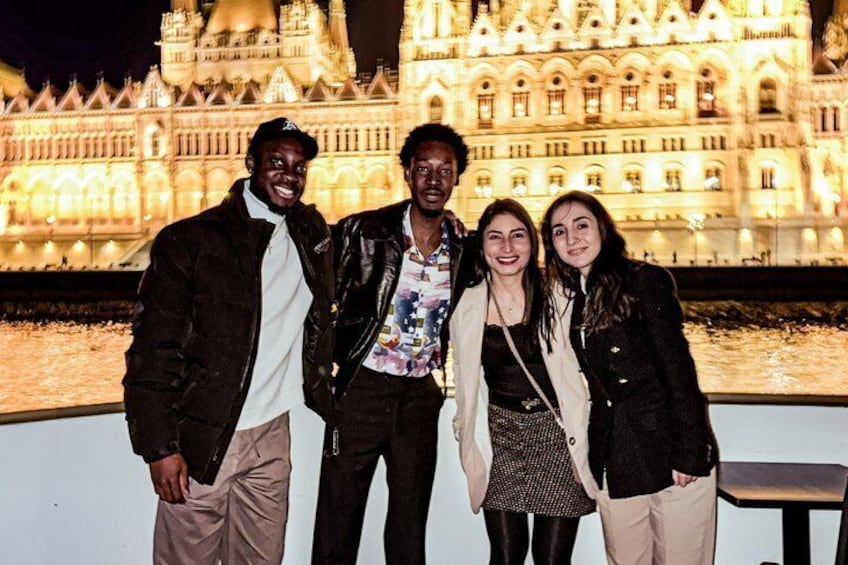 Four people standing in front of a brightly lit historic building at night. 4