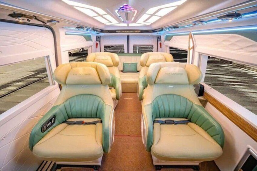 Interior de un tren con dos filas de asientos tipo salón VIP, iluminación en el techo y una ventana. 5