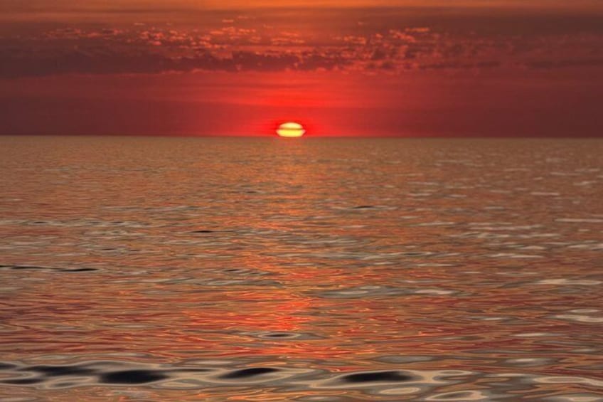 A sunset over the ocean with a visible sun reflection on the water. 3