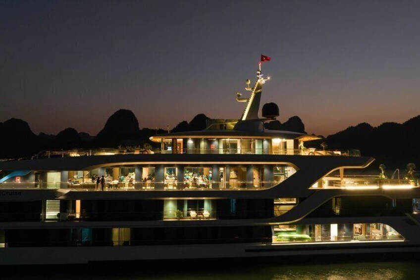 A large, illuminated yacht at night with multiple decks and a flag on top. 5