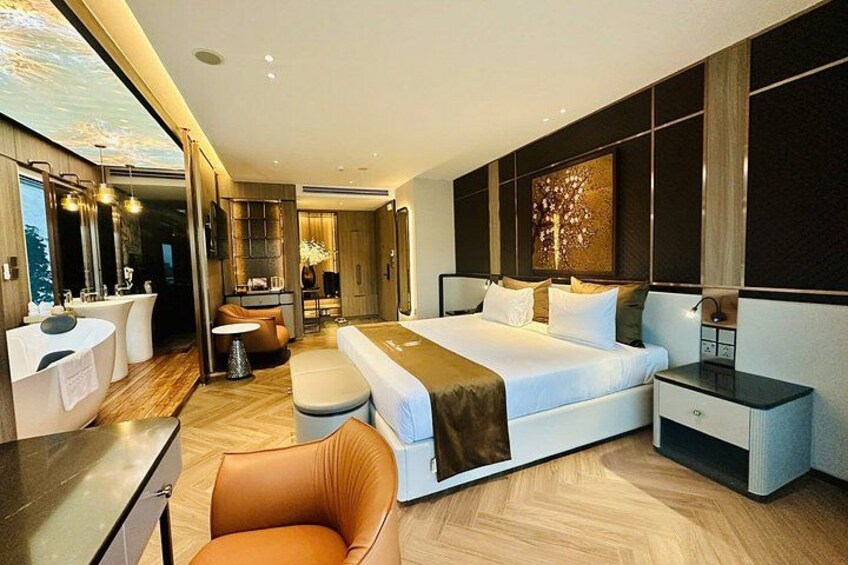 A modern bedroom with a large bed, a sitting area, and a bathroom. 3