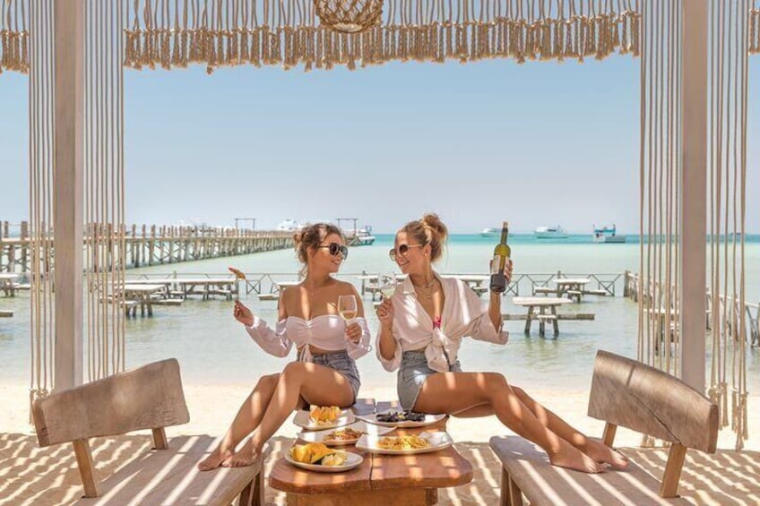 Deux personnes sont assises à une table, avec une vue sur la mer et une jetée en arrière-plan. 5