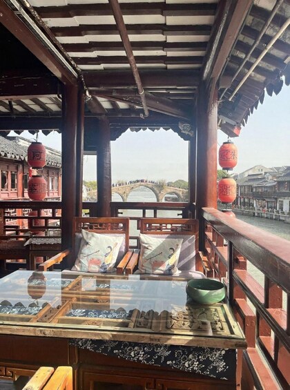 A traditional wooden pavilion with a view of a stone bridge and a river. 5