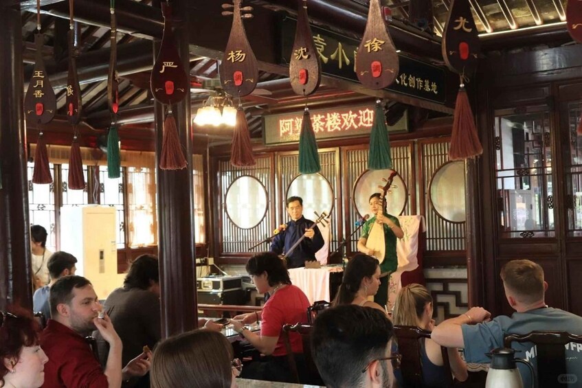 A traditional Chinese restaurant interior with wooden furniture, hanging decorations, and a live music performance. 5