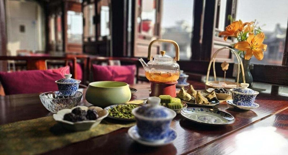 A traditional tea setting with various teaware and snacks on a wooden table. 5