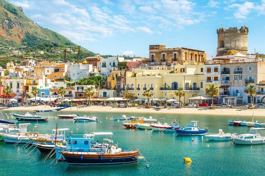 A coastal town with boats docked, colorful buildings, and a castle on a hill. 1