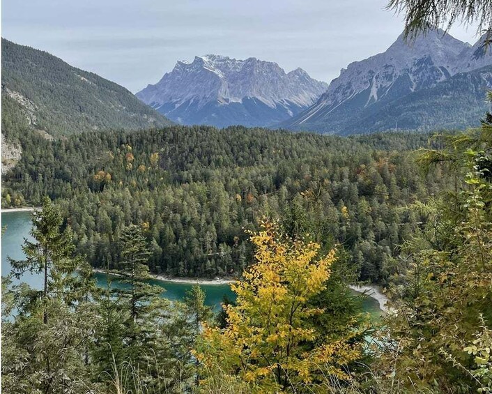 A mountainous landscape with dense forests, a lake, and distant peaks. 2