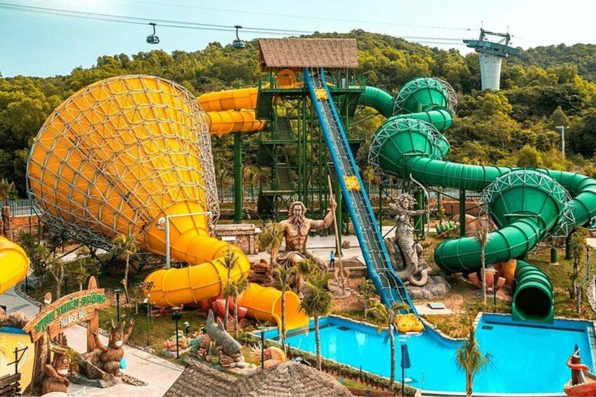 Parque acuático con un tobogán amarillo grande, toboganes de agua verdes y una zona de piscina. 2