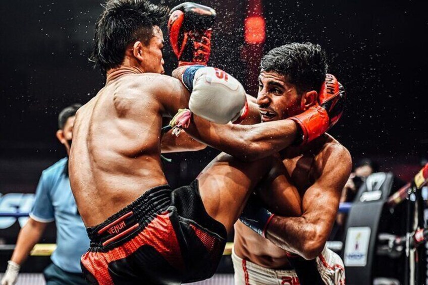 Two boxers in a fight, one wearing red and black shorts, the other in white and red. 4