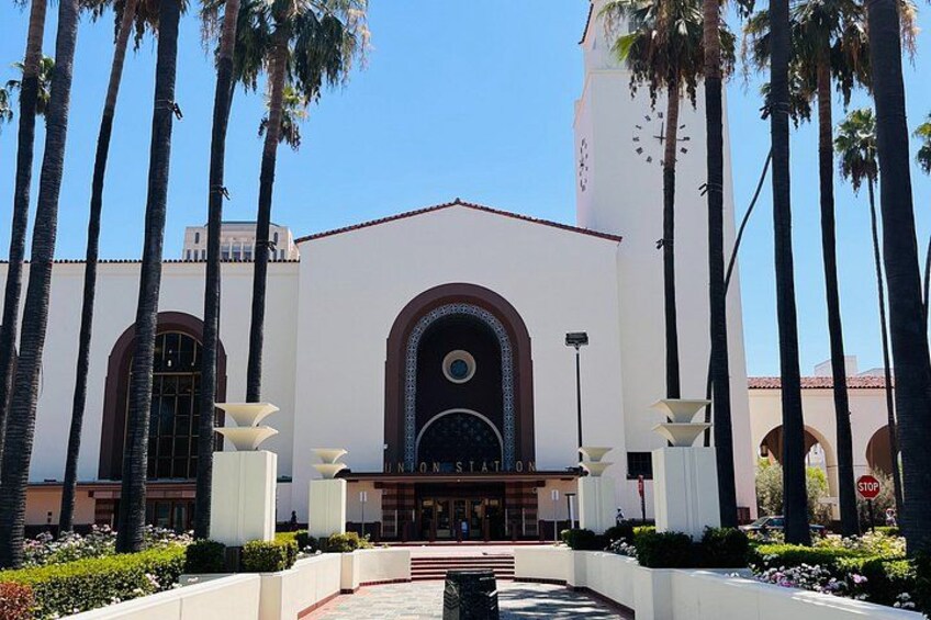 A building with a clock tower, palm trees, and a clear sky. 5