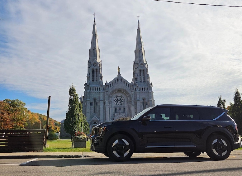 A black SUV parked in front of a large, ornate church with two tall spires and a circular window. 3