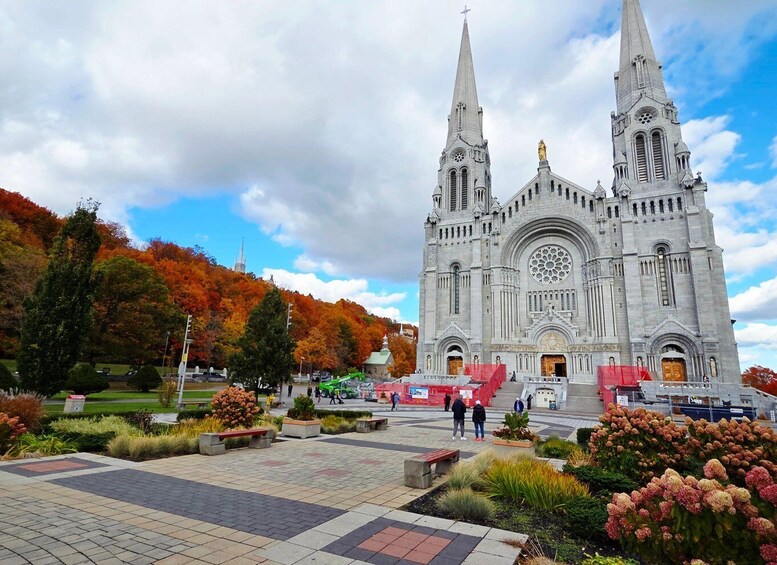 A grand cathedral with two spires, surrounded by a landscaped square with benches and flowering plants. 5