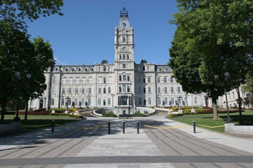 A grand building with a clock tower, surrounded by a well-maintained garden and a paved walkway. 3