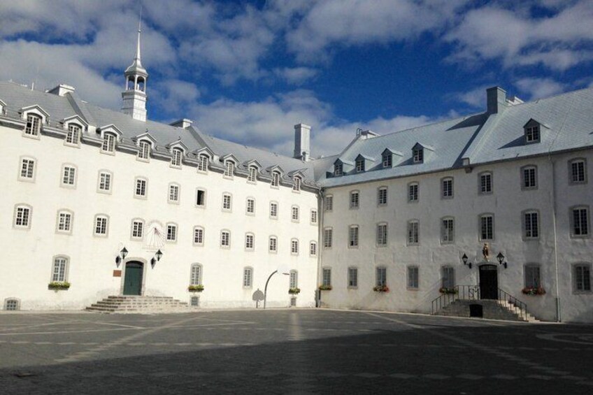 A large white building with a tower, a courtyard, and a clear sky. 2