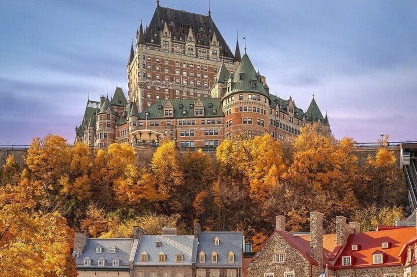 A historic building with a distinctive turreted roof, surrounded by autumn-colored trees. 1