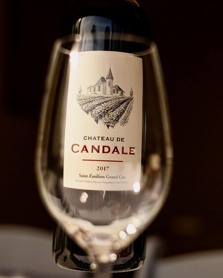 A wine bottle with a label featuring a château and vineyard illustration. 5