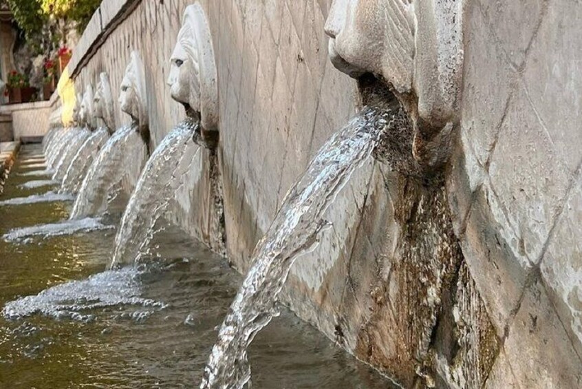 A series of water spouts with stone sculptures, flowing water, and a stone wall. 2