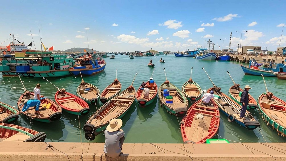 A harbor with small wooden boats docked, a larger fishing boat, and a distant hill. 2