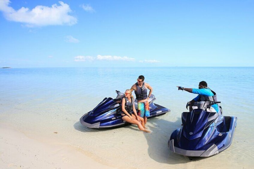 Dos motos acuáticas en una playa arenosa con agua tranquila y cielo despejado. 1
