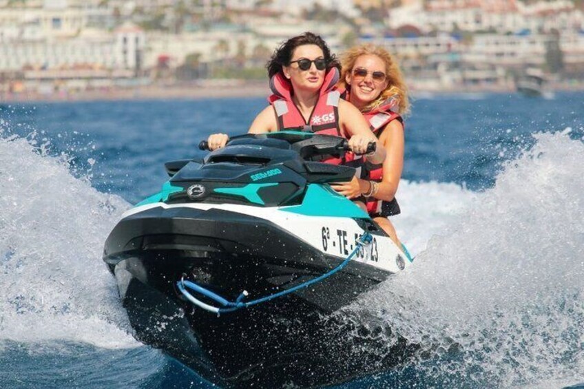 Dos personas en un jet ski, con un paisaje urbano al fondo. 3