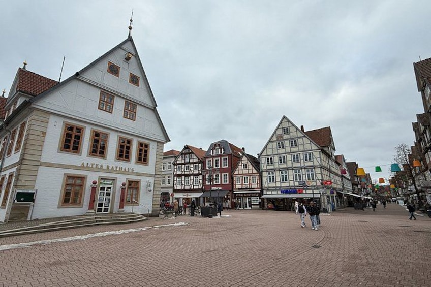 A European town square with traditional half-timbered buildings, cobblestone pavement, and a clear sky. 4