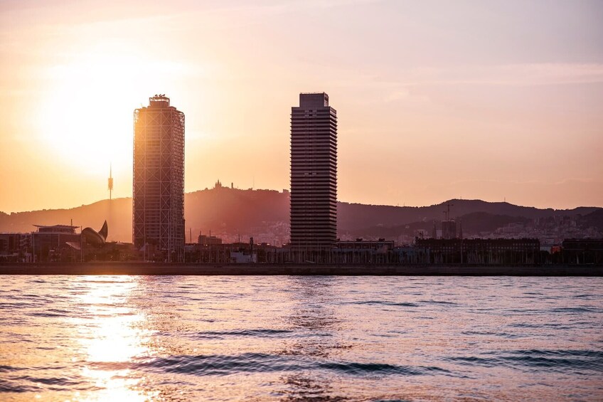 A cityscape with two prominent skyscrapers silhouetted against a sunset. 1