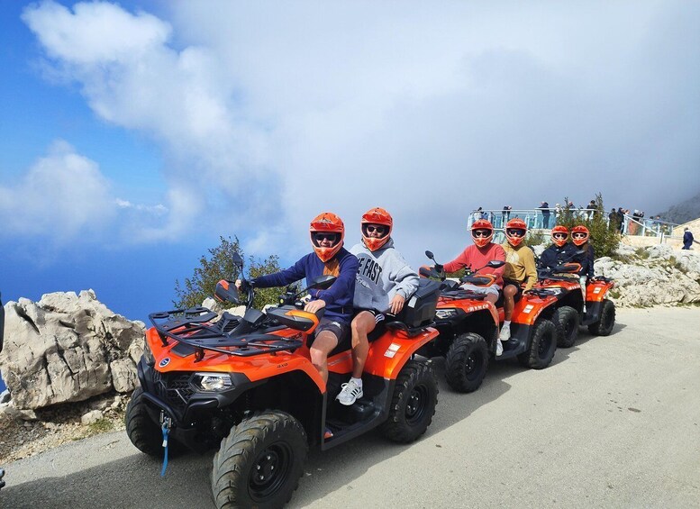 A group of people on ATVs on a paved road with a rocky landscape and a clear sky in the background. 1