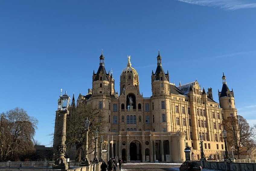 A large, ornate building with multiple towers and a central dome, surrounded by a fence and trees. 5