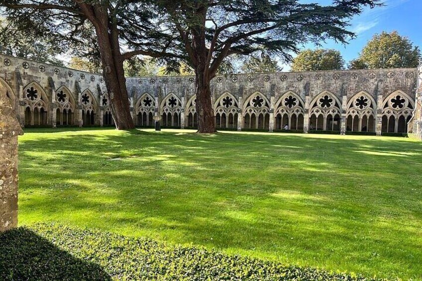 A courtyard with a stone wall featuring arched windows and a grassy lawn. 5