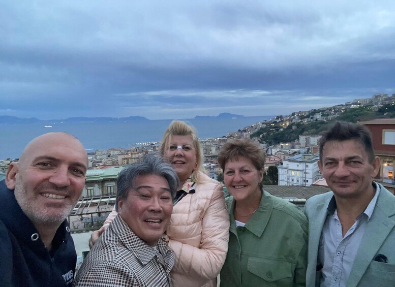 A group of people on a rooftop with a cityscape and mountains in the background. 3