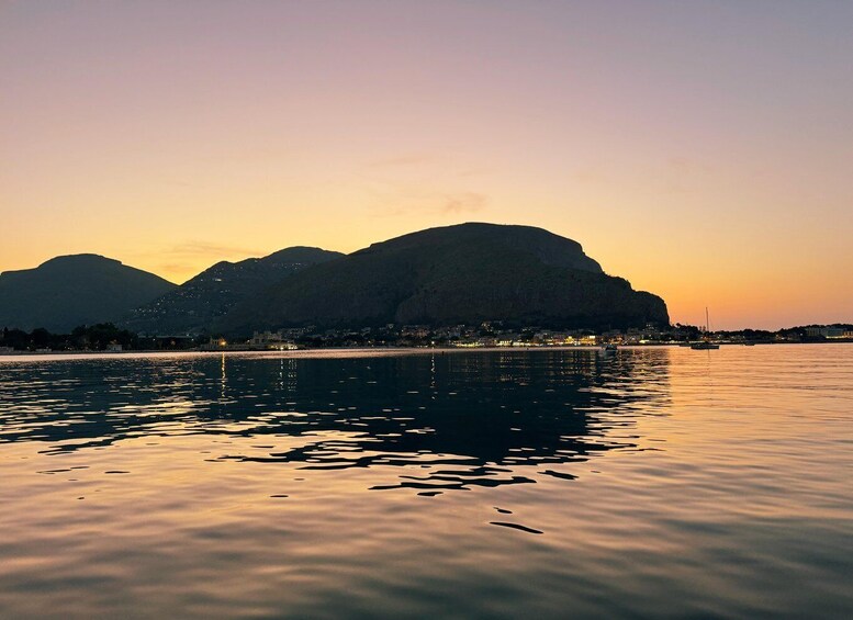 A calm body of water reflecting mountains at sunset. 3