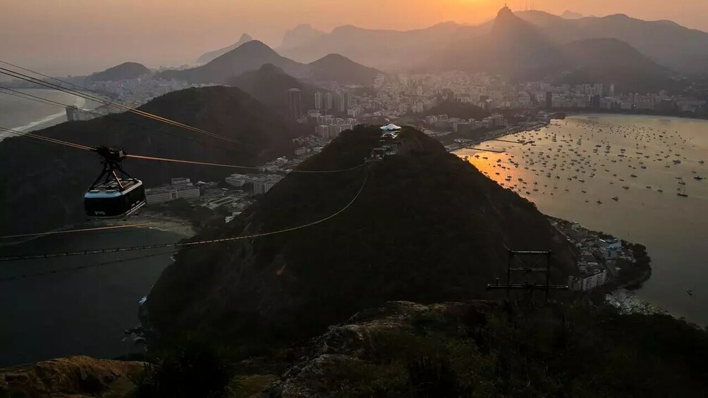 A cable car system over a mountainous landscape with a city and river below. 4