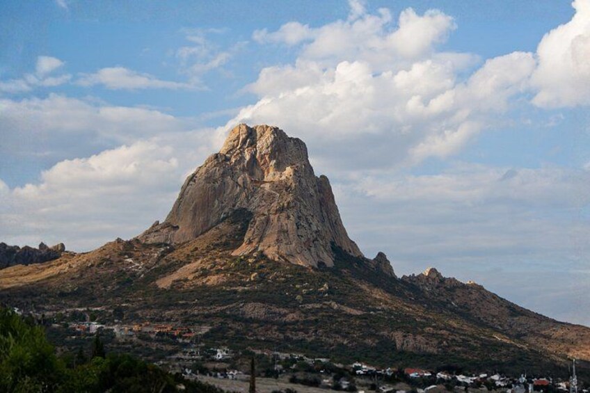 Ein Berg mit einem markanten Gipfel, eine Stadt am Fuße und ein teilweise bewölkter Himmel. 5