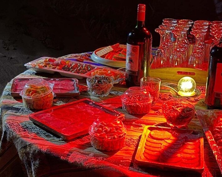 A table with various food items, a bottle of wine, and multiple glasses. 5