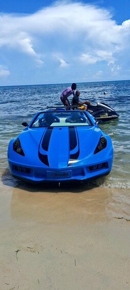 Un coche deportivo azul estacionado en una playa arenosa, con el océano al fondo. 5