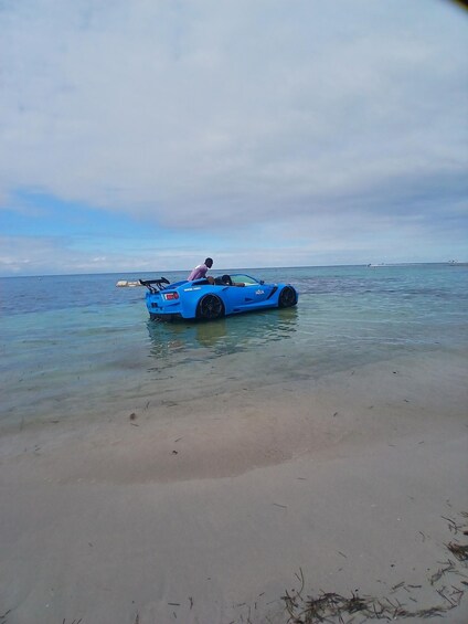 Un coche deportivo azul parcialmente sumergido en aguas poco profundas en la playa. 4